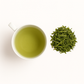 Cup of bright green sencha tea with loose leaves on a ceramic tray; Japanese green tea rich in EGCG for skin protection and antioxidant defense