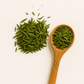 Cup of bright green sencha tea with loose leaves on a ceramic tray; Japanese green tea rich in EGCG for skin protection and antioxidant defense