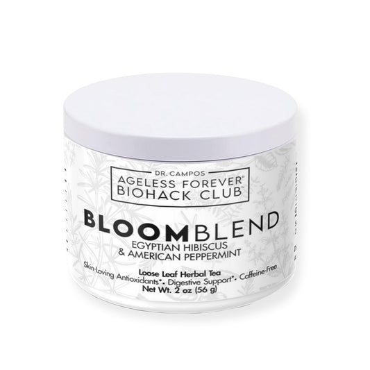 Glass cup of BloomBlend hibiscus and peppermint tea beside loose leaves; vibrant herbal tea for skin clarity and anti-inflammatory benefits